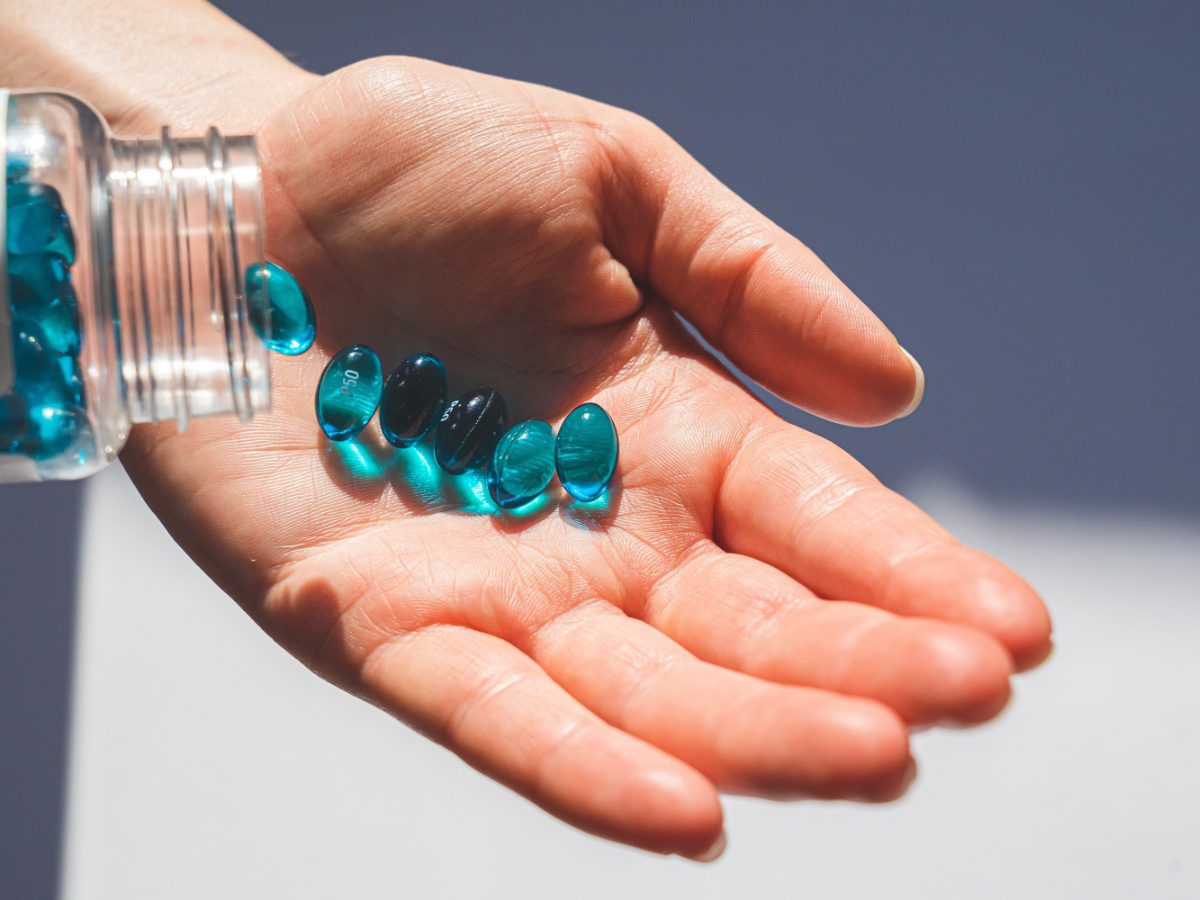 person dropping blue sleeping pills into their palm